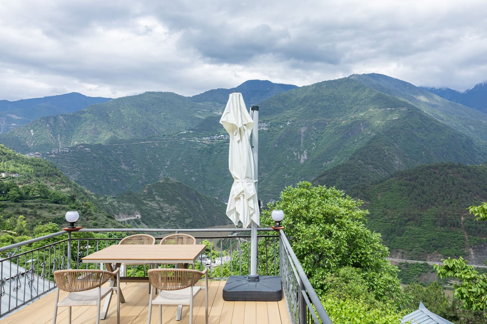 Jilin Mountain Lodge — the terrace at the edge of the hill, forested ridges across the Lancang valley under a cloudy sky