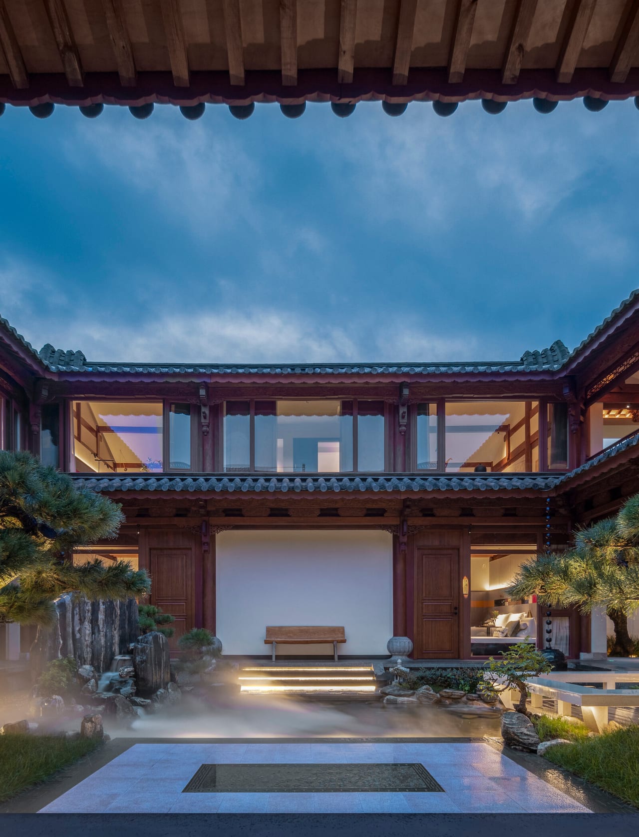 Kogongdi — the courtyard lit at blue hour, the upper gallery glowing above the pool