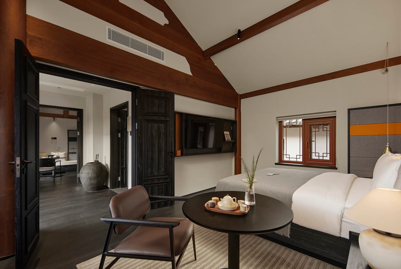 Kogongdi — guest room with a sitting corner beneath exposed beams, courtyard beyond