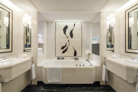 The Peninsula Beijing — a marble bathroom with twin vanities either side of a deep bathtub