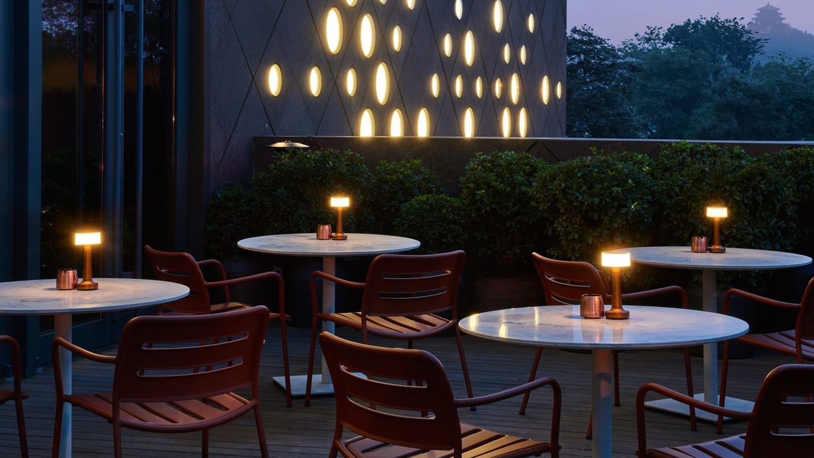 The PuXuan Hotel and Spa, Beijing — an outdoor terrace at dusk, the pavilion on Jingshan's hill beyond the trees