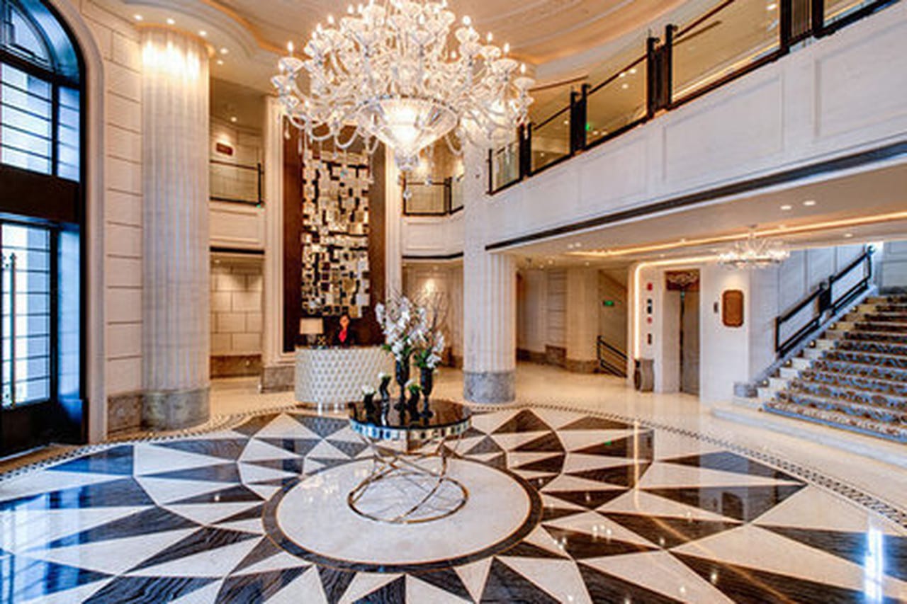 Sofitel Legend People's Grand Xi'an — the double-height lobby, a crystal chandelier above a black-and-white marble floor laid in a starburst, fluted columns and a carpeted staircase rising to the gallery
