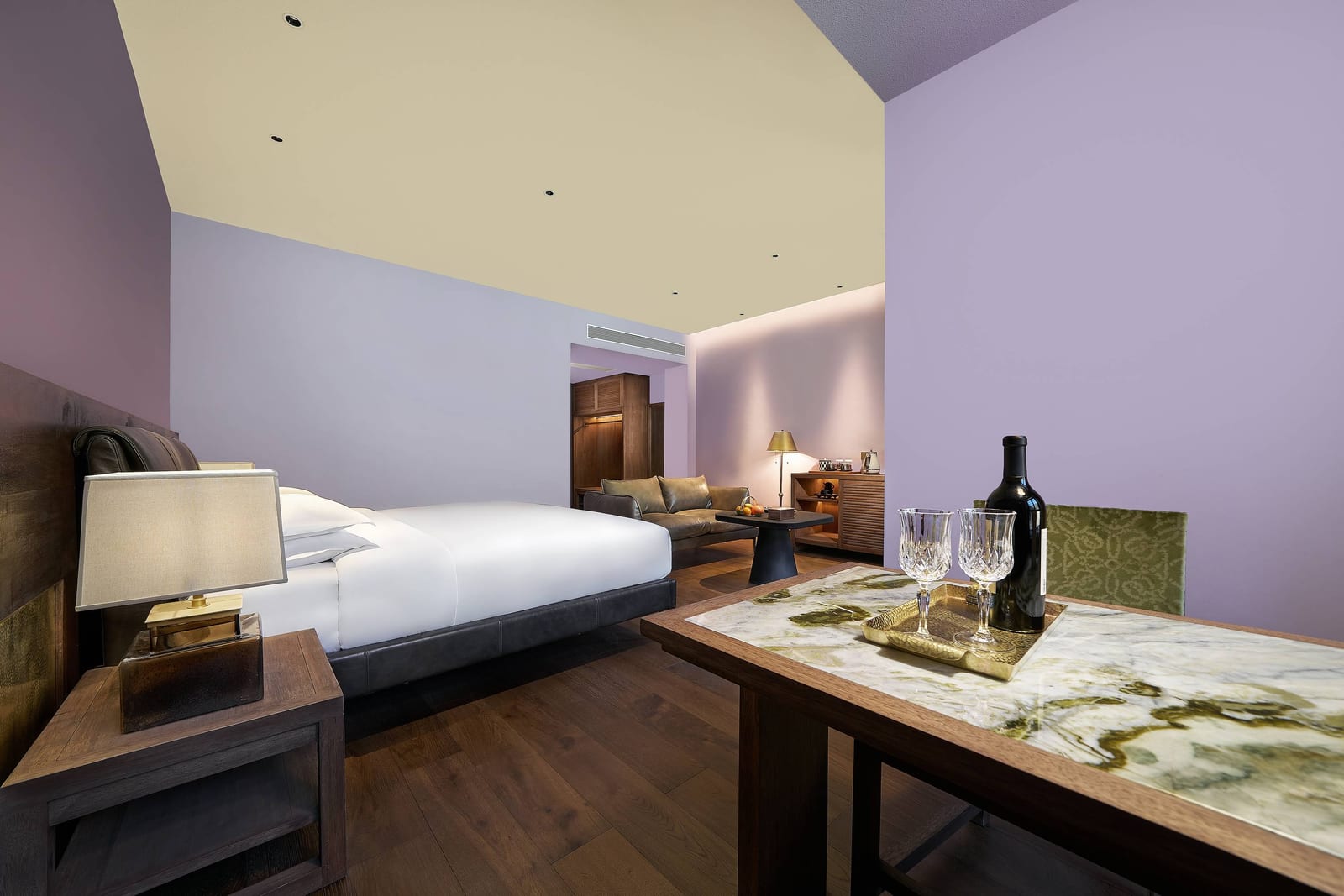 Songtsam Lodge Cizhong — a Deluxe room in lilac and grape purple, a bottle of wine and glasses on the desk and the bed beyond