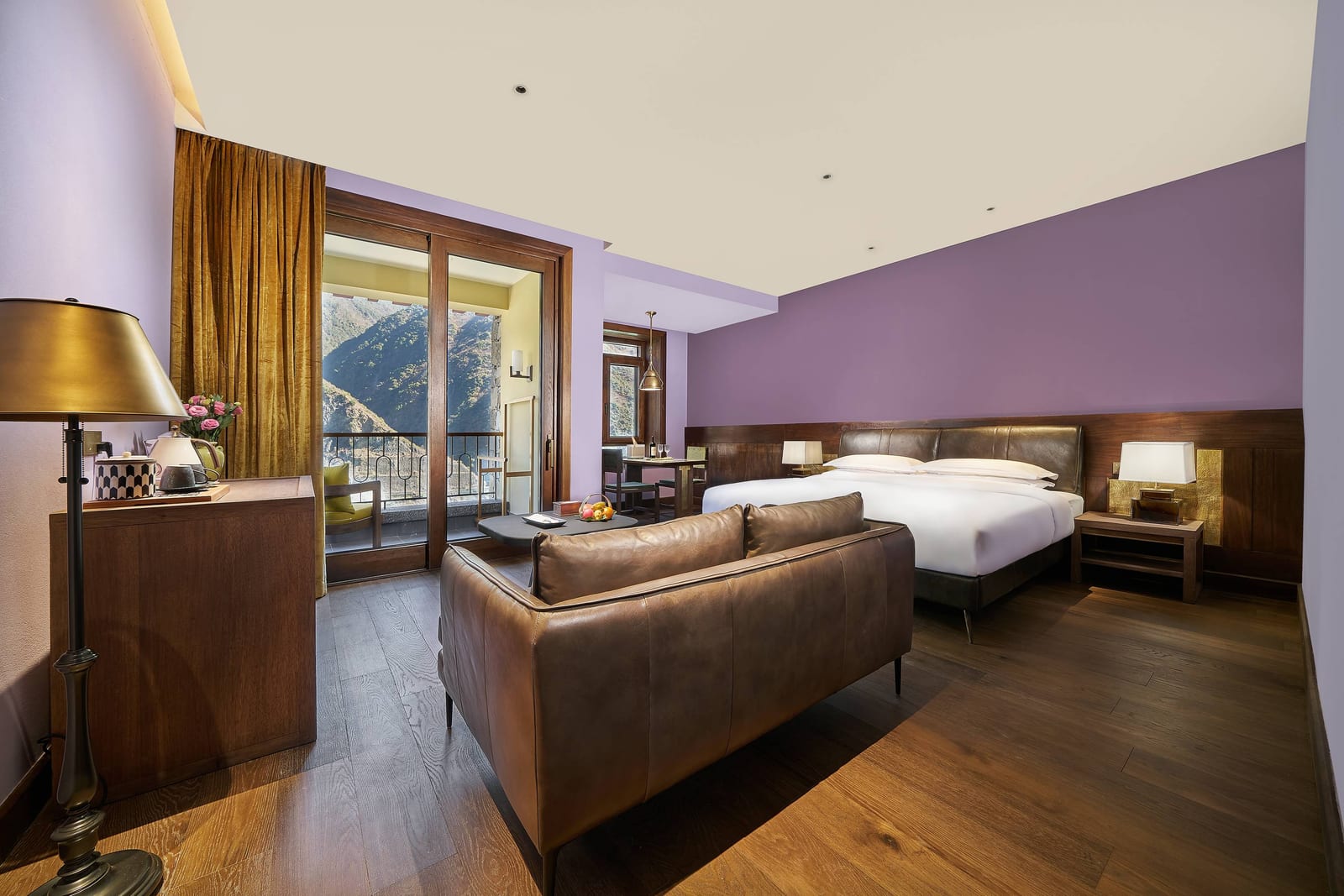 Songtsam Lodge Cizhong — a Deluxe twin room with purple walls, gold velvet curtains, a leather sofa and glass doors onto a balcony over the valley