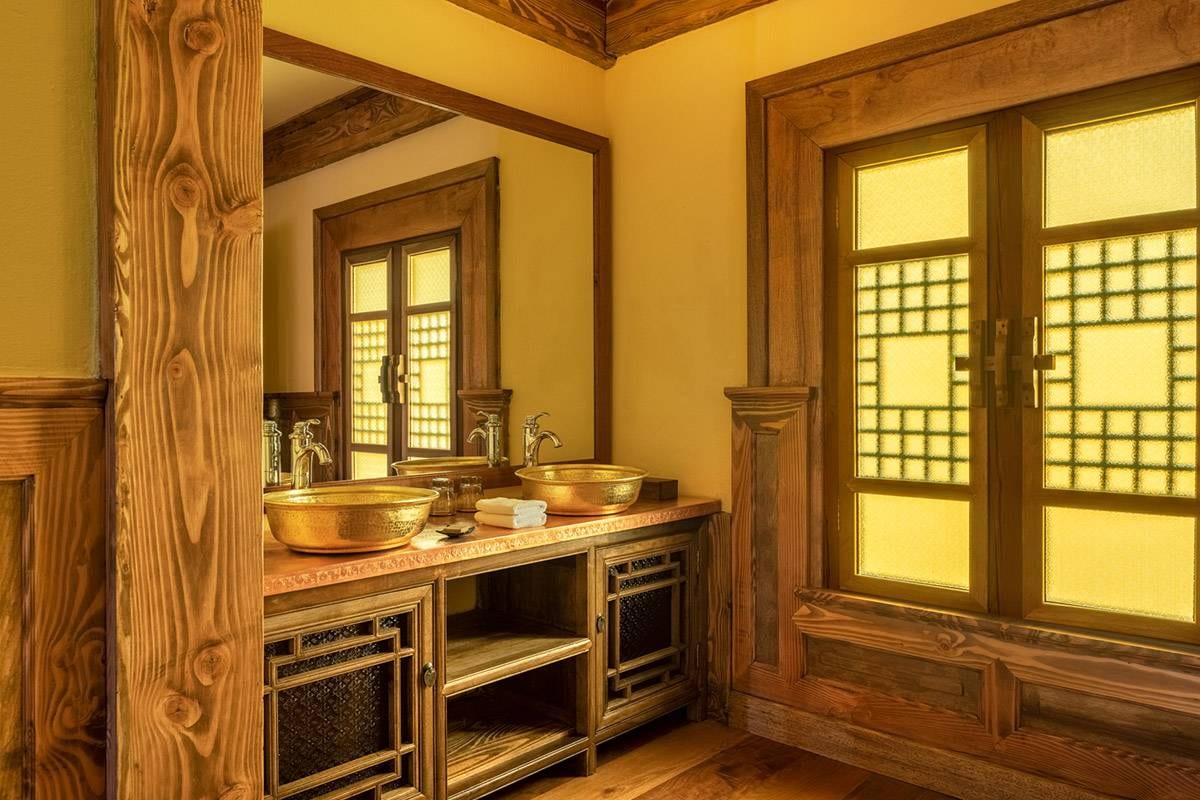 Songtsam Lodge Shangri-La — twin hammered-brass basins on a timber vanity beside latticed windows