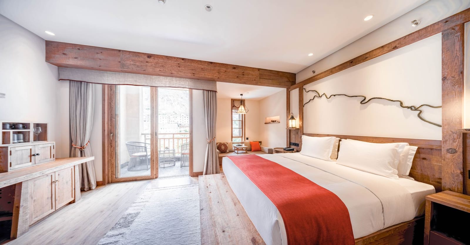 Tea Horse Road Benzilan — a king room with a red runner on white linen, a line drawing of a winding river above the bed and a balcony door onto the hills