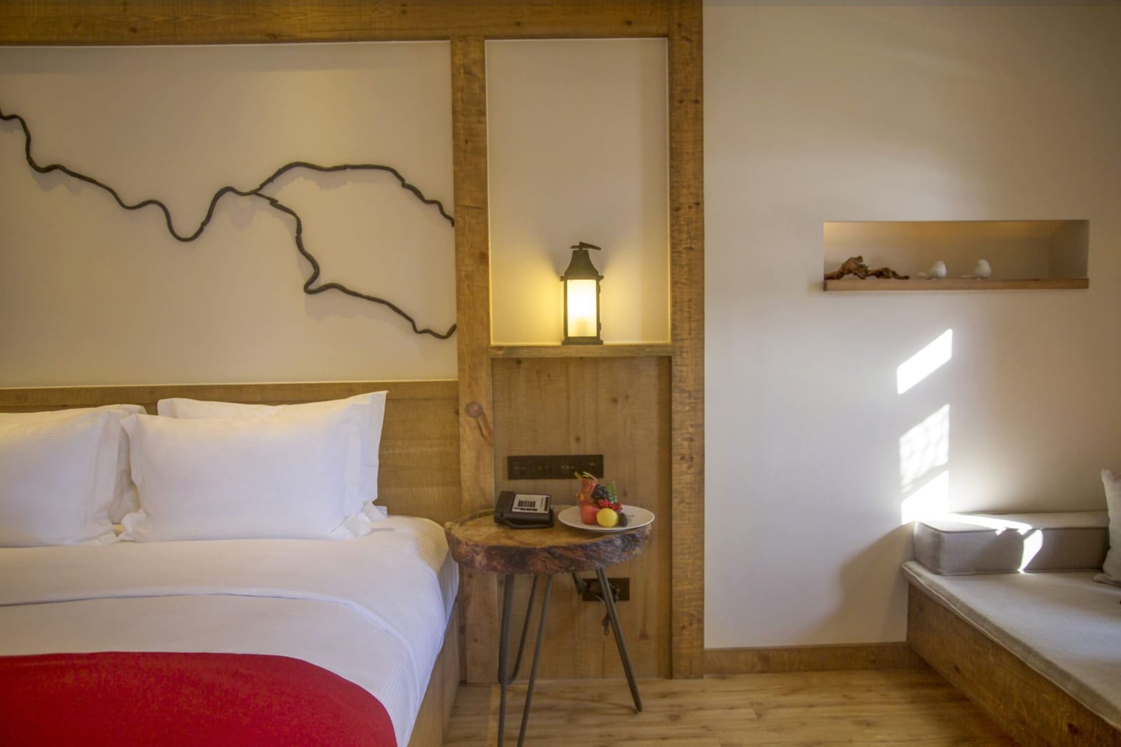 Tea Horse Road Benzilan — a lantern on the timber headboard wall, a tree-stump side table with fruit and a cushioned window seat