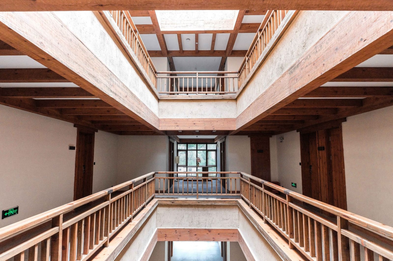 Tea Horse Road Benzilan — the galleried timber atrium at the heart of the lodge, balustraded walkways on three floors under a skylight