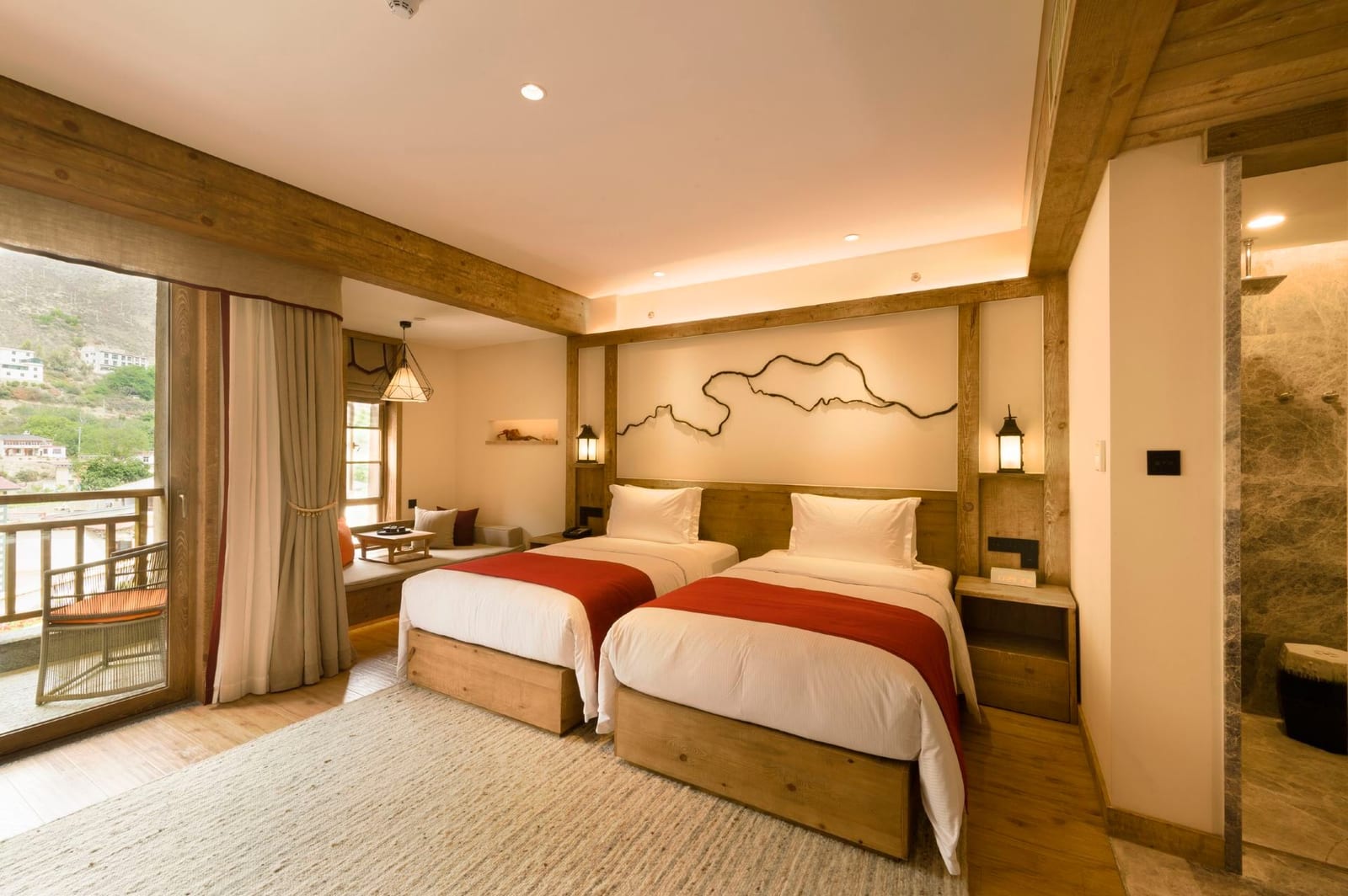 Tea Horse Road Benzilan — a twin room with red bed runners, a wandering line drawn across the headboard wall and a balcony onto the valley