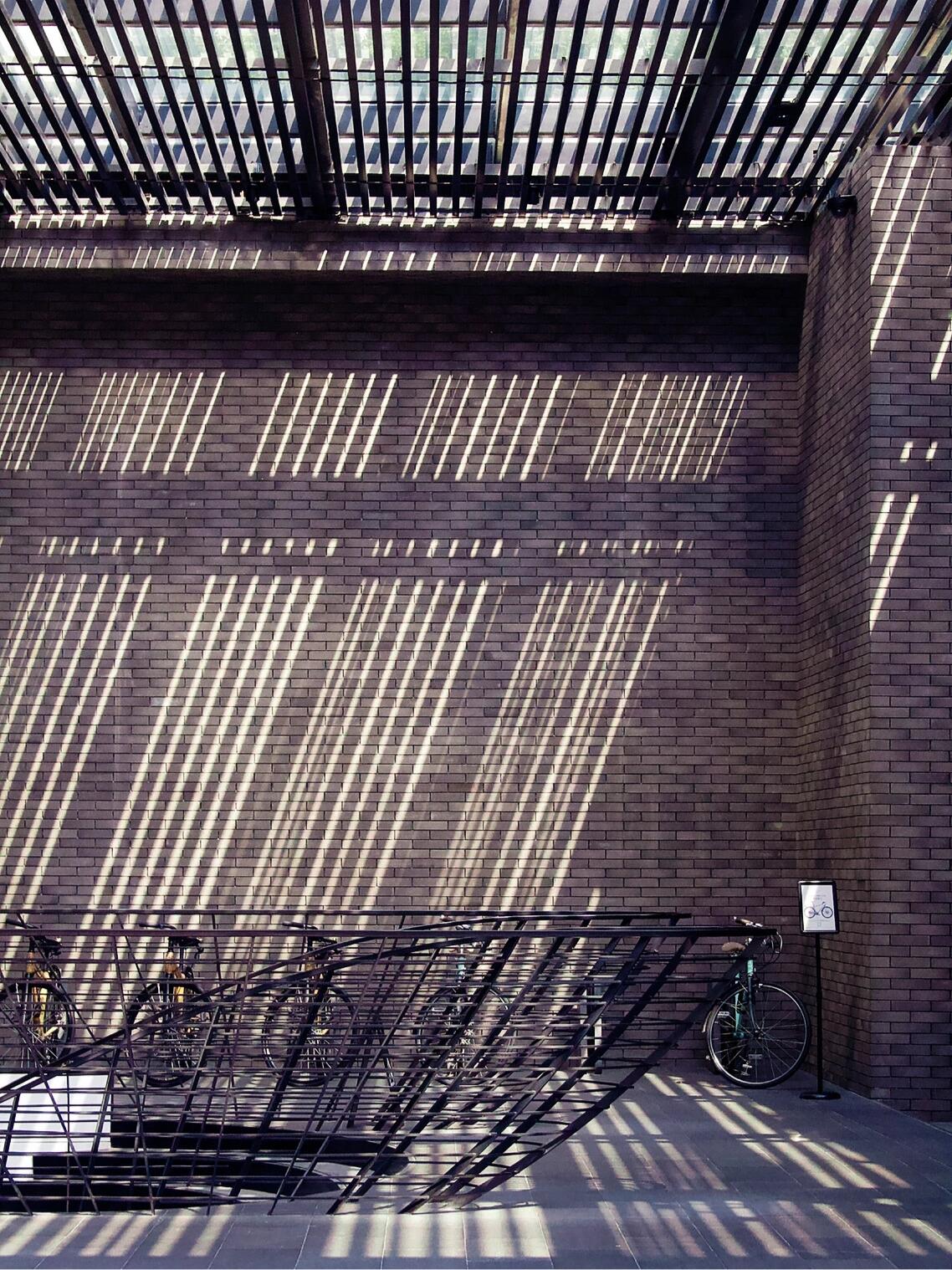 Brick-and-louvre facade at The Temple House Chengdu — bicycles parked along the ground-floor corridor