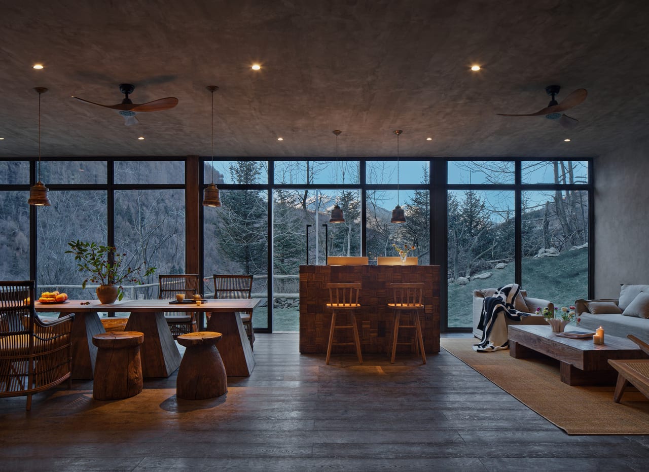 Vacilando Siguniang — the bar and lounge at dusk behind a full-height glass wall, Mount Siguniang beyond