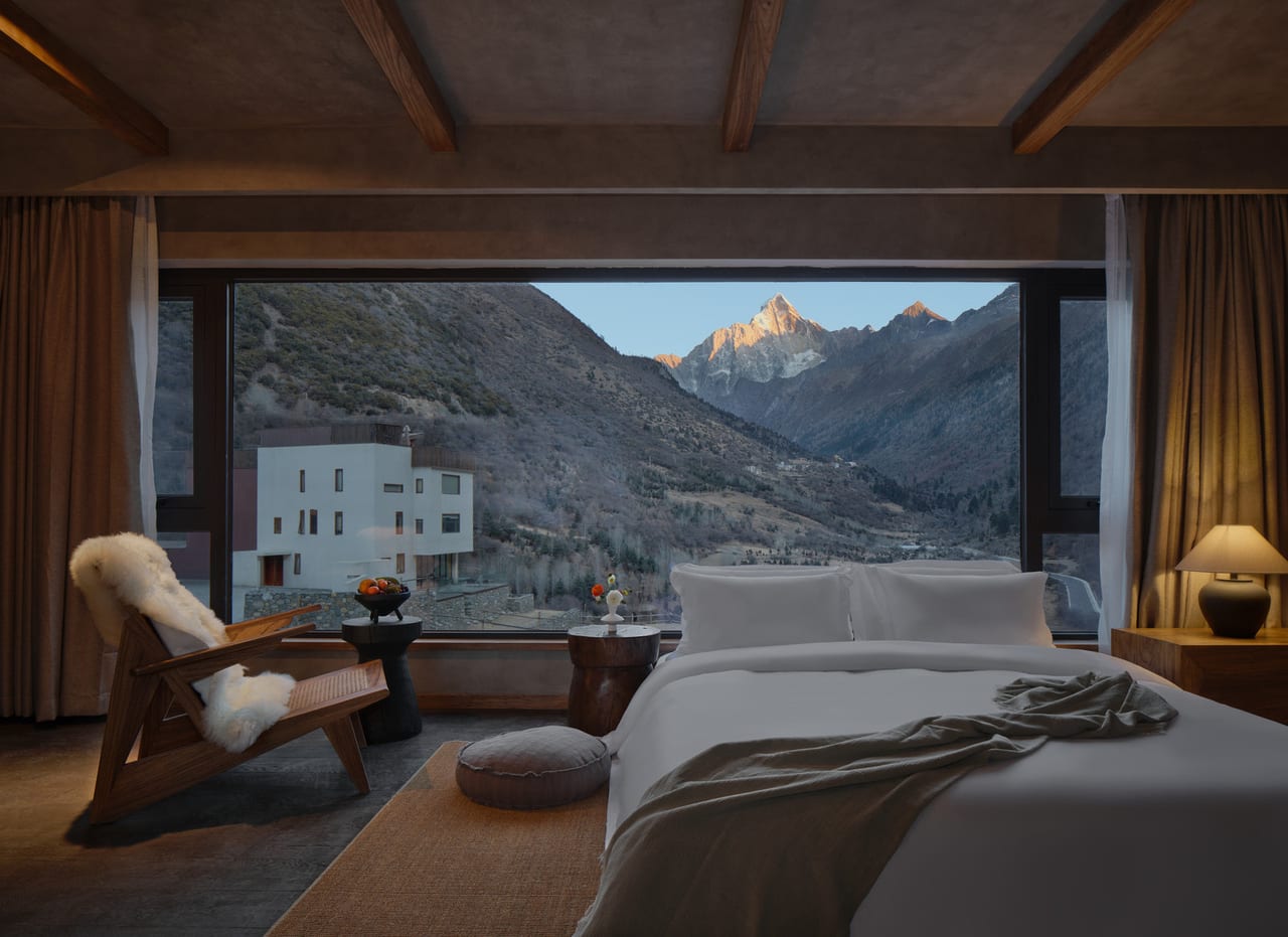 Vacilando Siguniang — bed set against a picture window framing the snow peak above the Changping valley