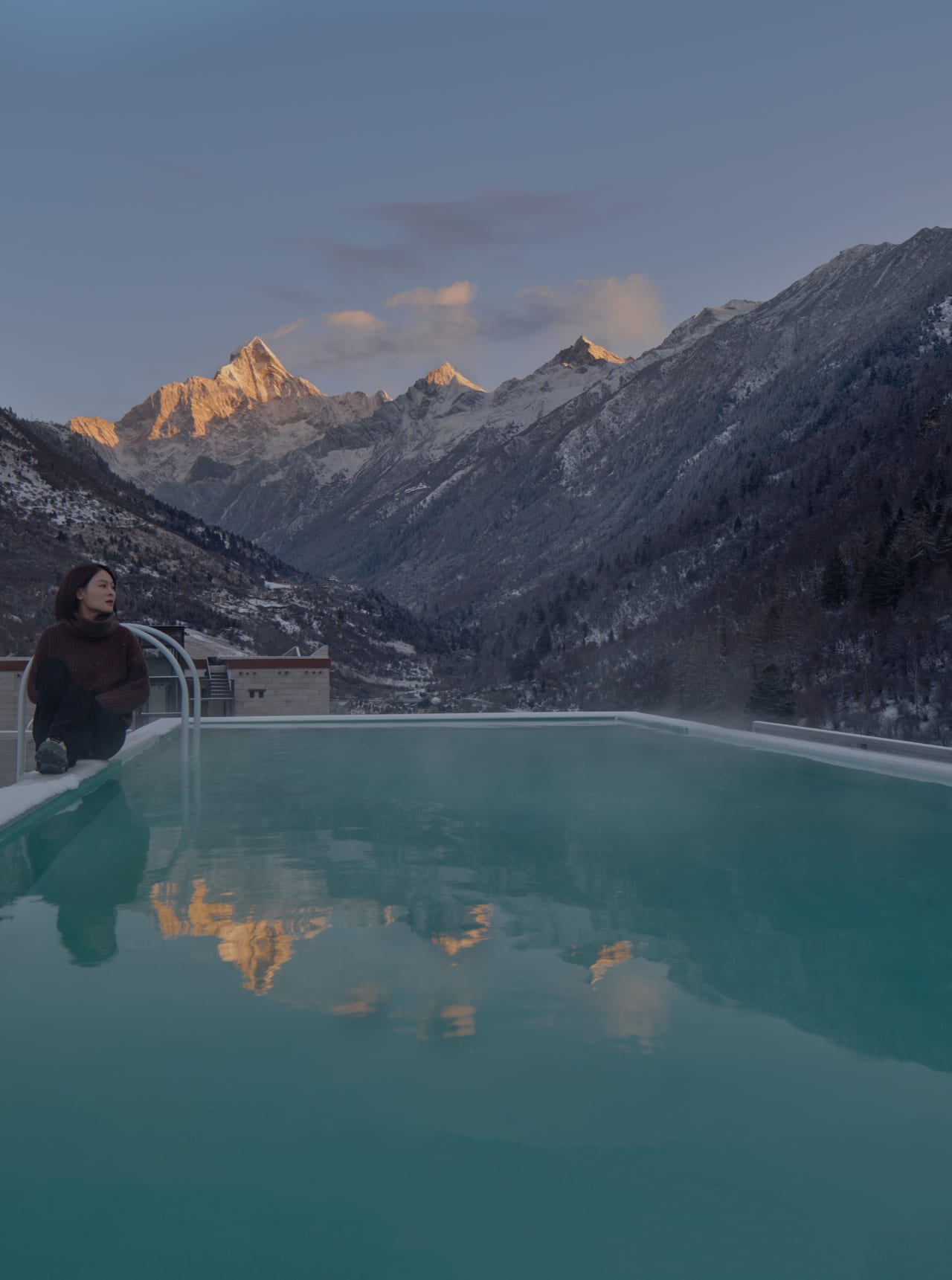 Vacilando Siguniang — the open-air rooftop pool at dusk, alpenglow on the peaks above Changping Valley
