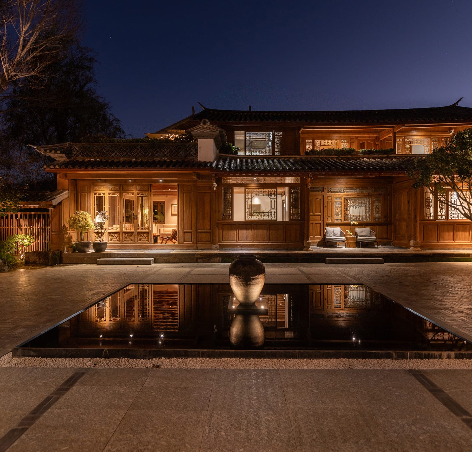 Wuliu Xinsu — the main house lit at night, reflected in the courtyard pool