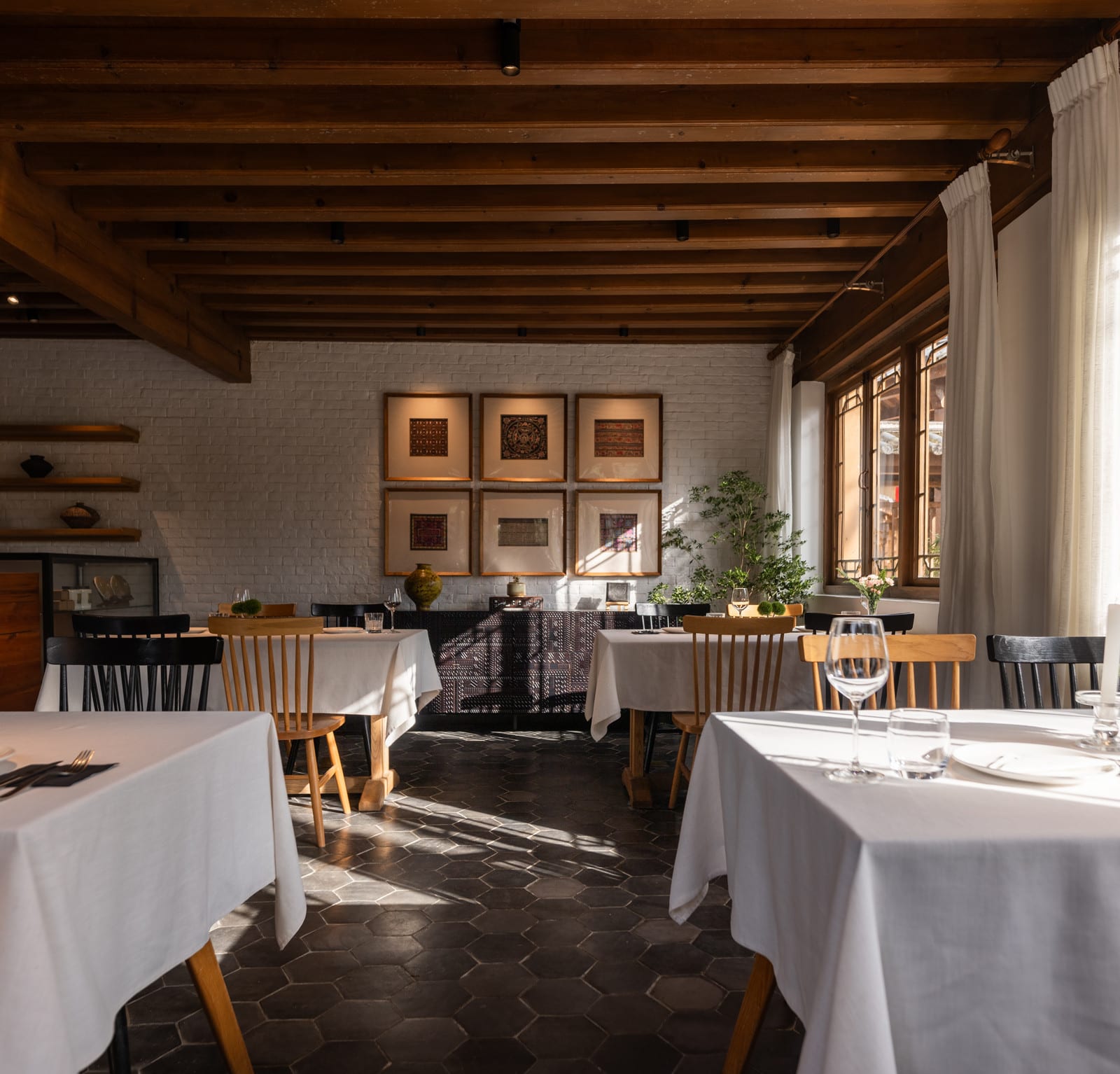 Wuliu Xinsu — the dining room where breakfast is served, white tablecloths under a beamed ceiling