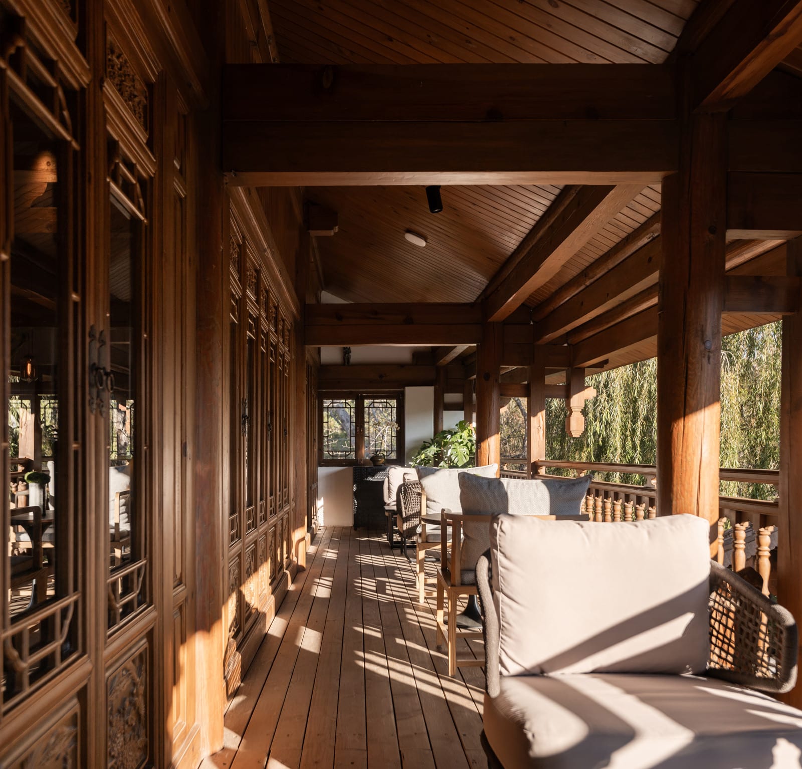 Wuliu Xinsu — the timber gallery with lattice windows and a sofa in the afternoon light