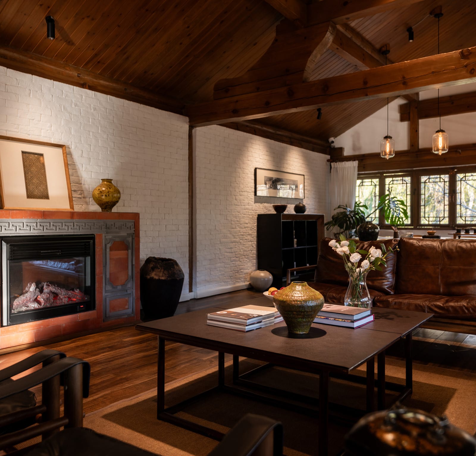 Wuliu Xinsu — the lounge with a fireplace, leather sofas and books under timber beams