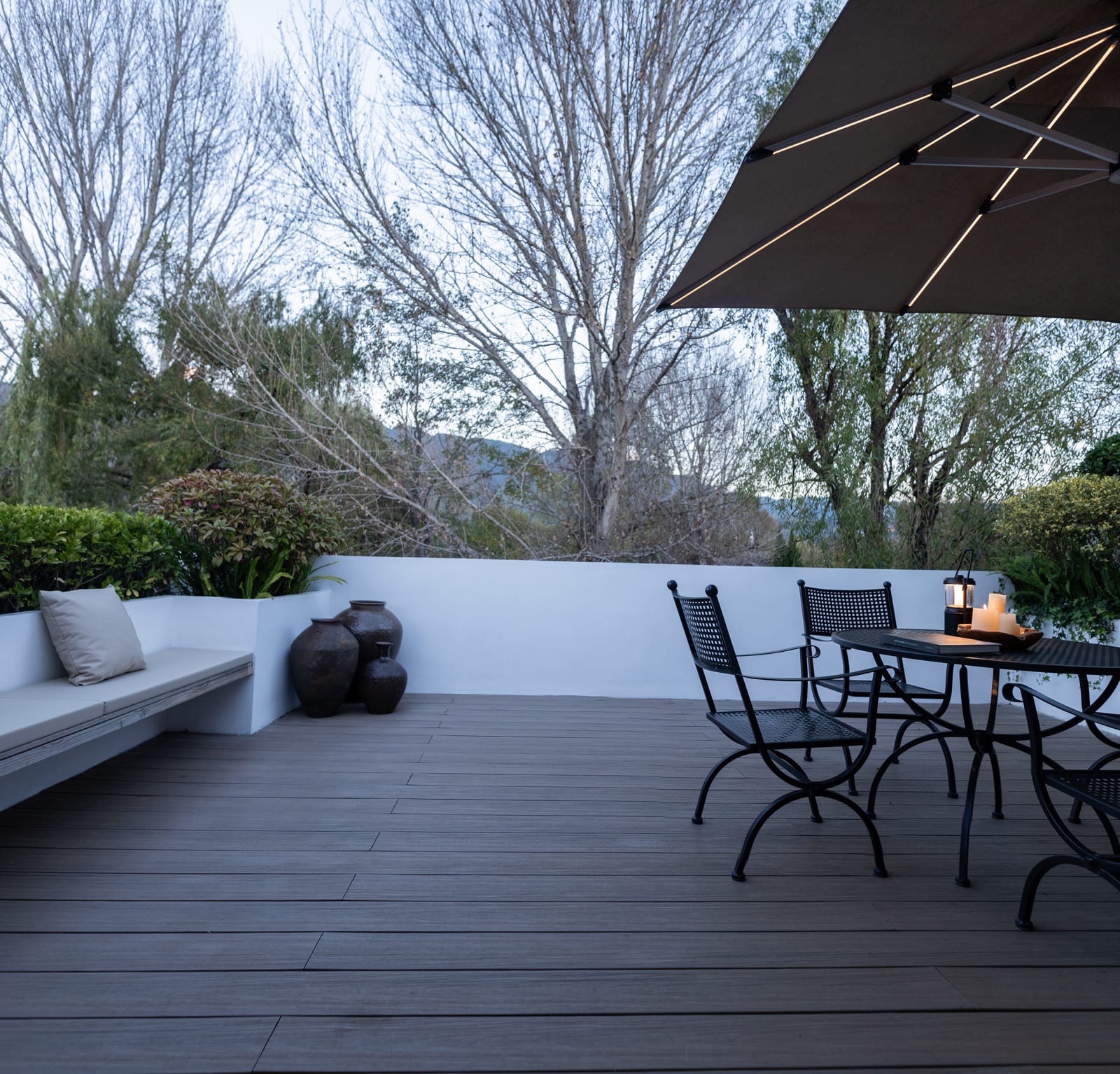Wuliu Xinsu — the terrace with a table, chairs and a parasol among the trees