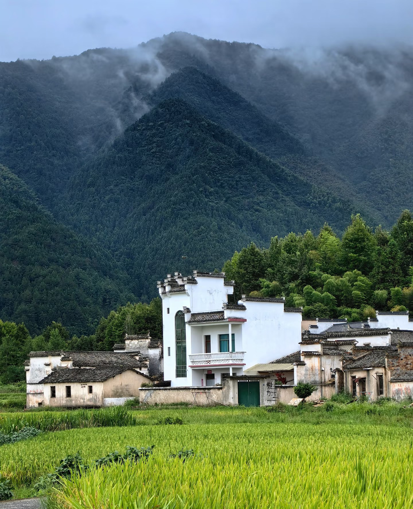 A whitewashed Huizhou village below misty green mountains